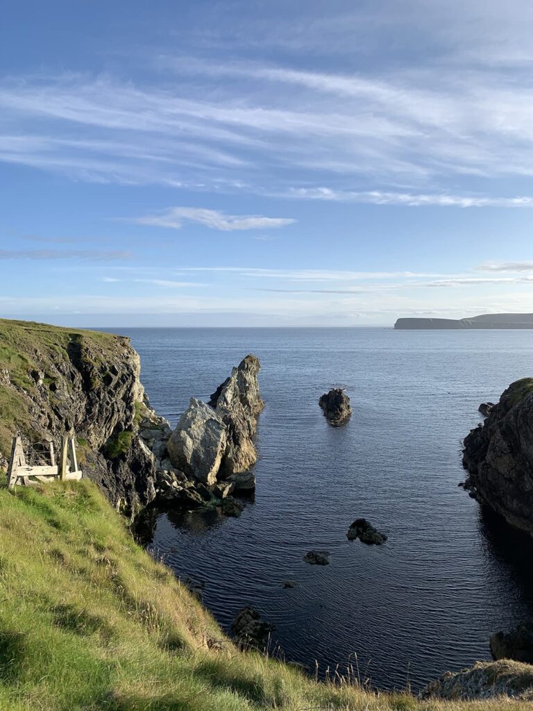 Landscape scene from the 7 mile walk around Funzie Ness, Shetland, showing cliffs, open sea and the mainland of Shetland on the horizon.