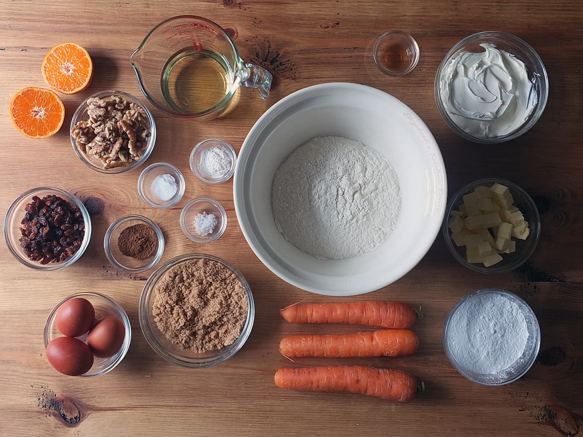 Top down image showing all the recipe ingredients needed to make a carrot cake with cream cheese frosting.