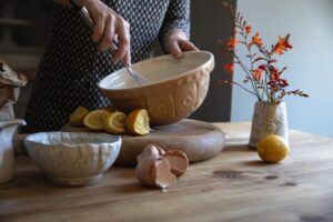 Image of Elizabeth Atia's hands whisking ingredients in a ceramic bowl with squeezed lemon halves next to it.