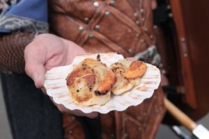 Image of two pan-seared scallops with the roe intact presented in a scallop shell by a man in Viking clothes.