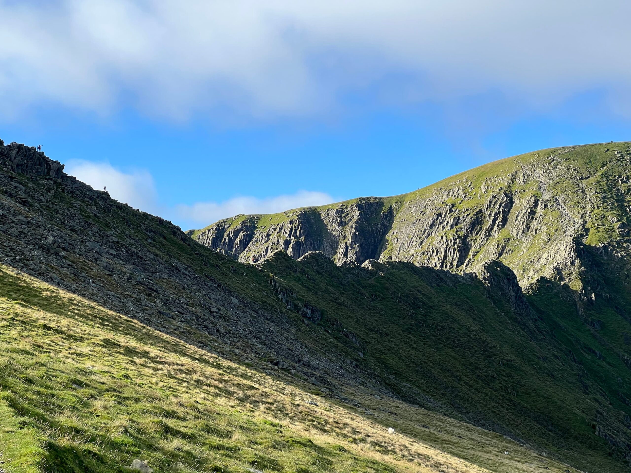 Image of the sharp edge of Striding Edge, a one-mile stretch of land. You can see a few walkers, very tiny, scrambling across the top of it.