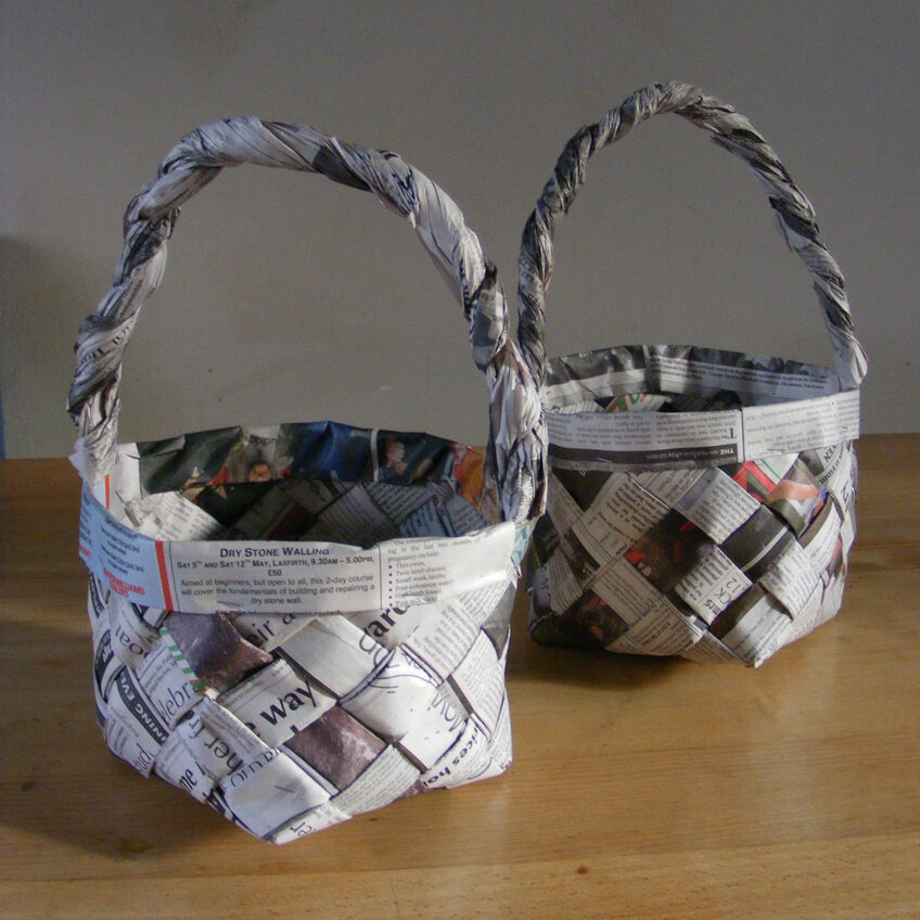Image of two finished woven newspaper baskets with handles.