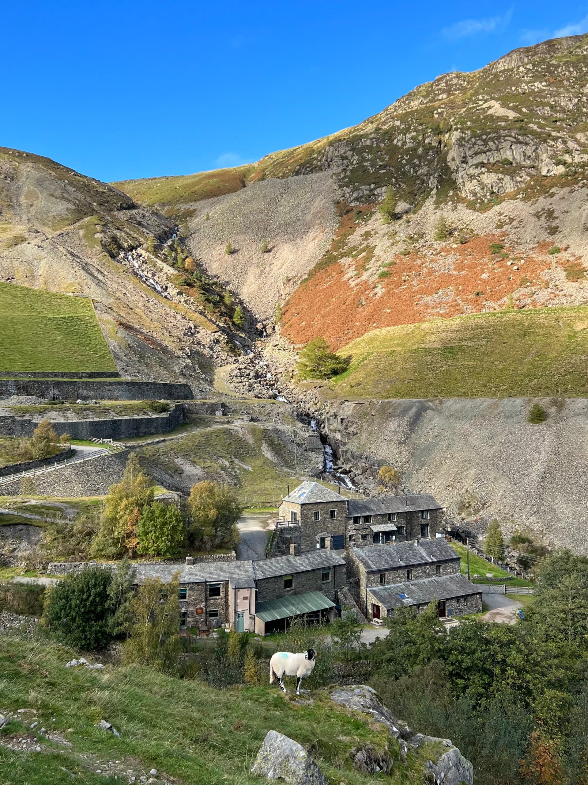 Image of old stone buildings at Greenside Mine with a stream coming down the hills in the background.