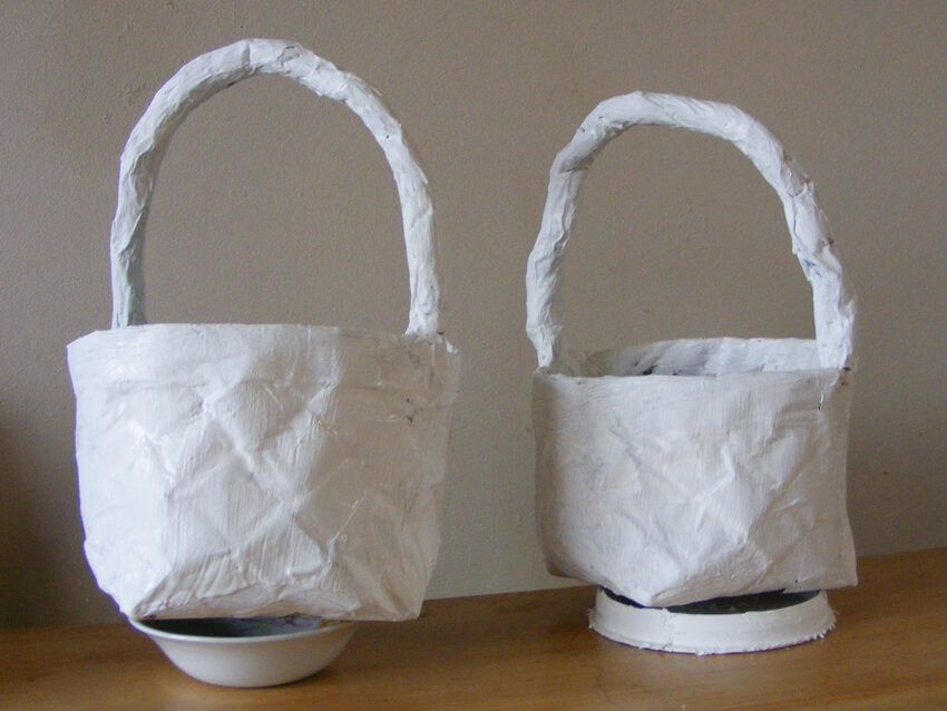 Image of two finished newspaper baskets painted white.