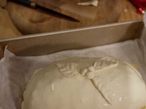 Image of holly leaf and berry puff pastry decorations on top of turkey wellington.