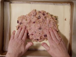 Image of pork sausagemeat spread out onto a layer of puff pastry.