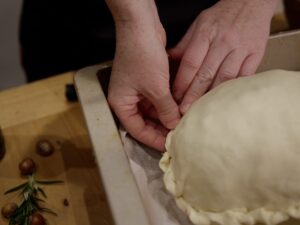 Image of hands crimping layers of puff pastry together.