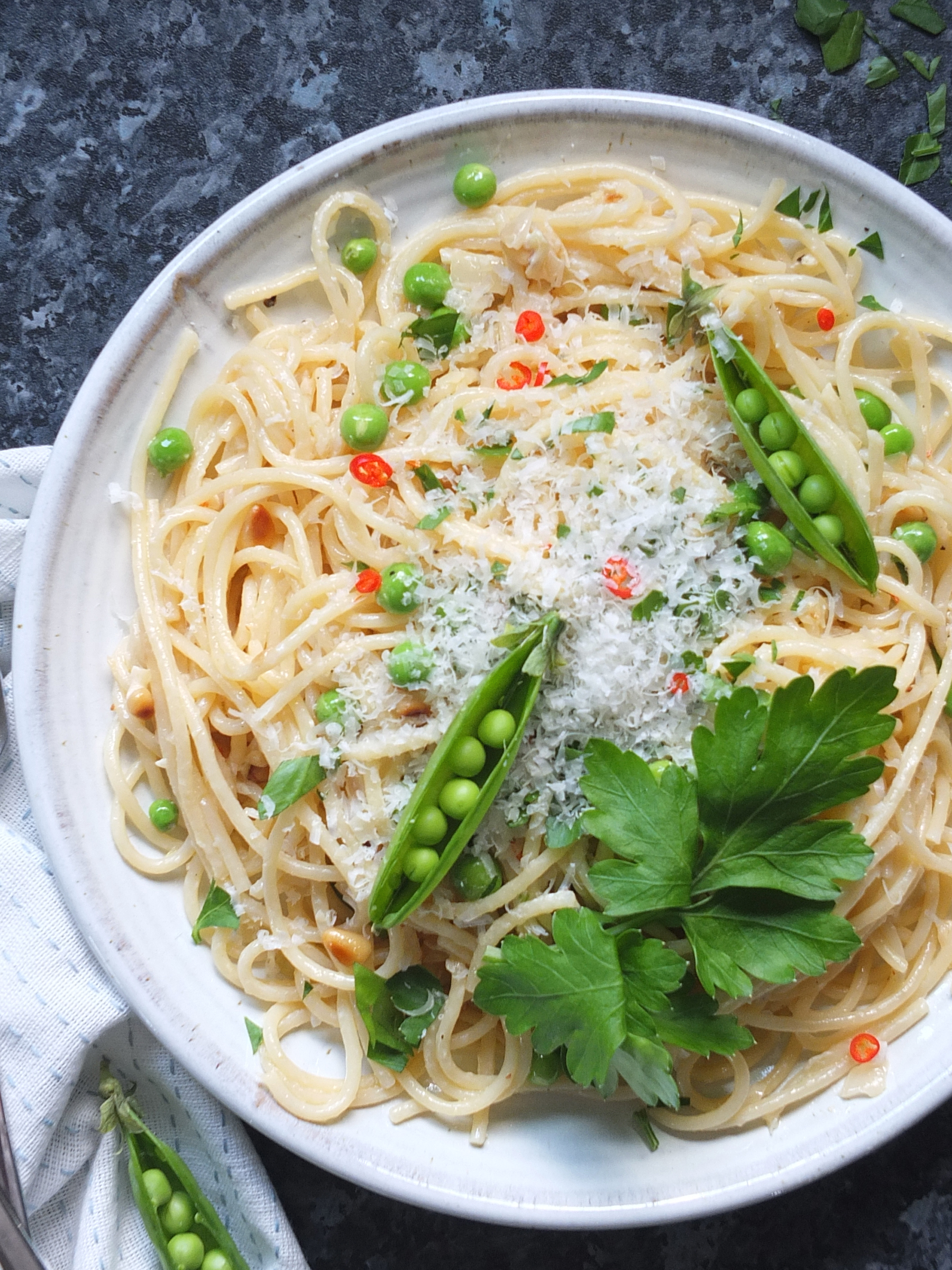 Close up image of spaghetti pasta with green peas recipe. There are two open pea pods as a garnish on the top, it's pretty.