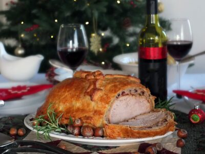 Image of turkey Wellington with a slice out of it showing the layers of roast turkey, stuffing and crisp pastry.