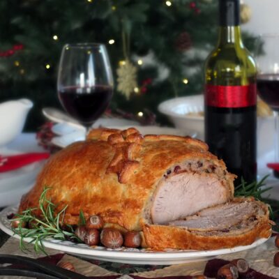 Image of turkey Wellington with a slice out of it showing the layers of roast turkey, stuffing and crisp pastry.