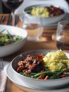 Image of vegan mushroom bourguignon served on a plate with green beans almondine and creamy mashed potatoes.